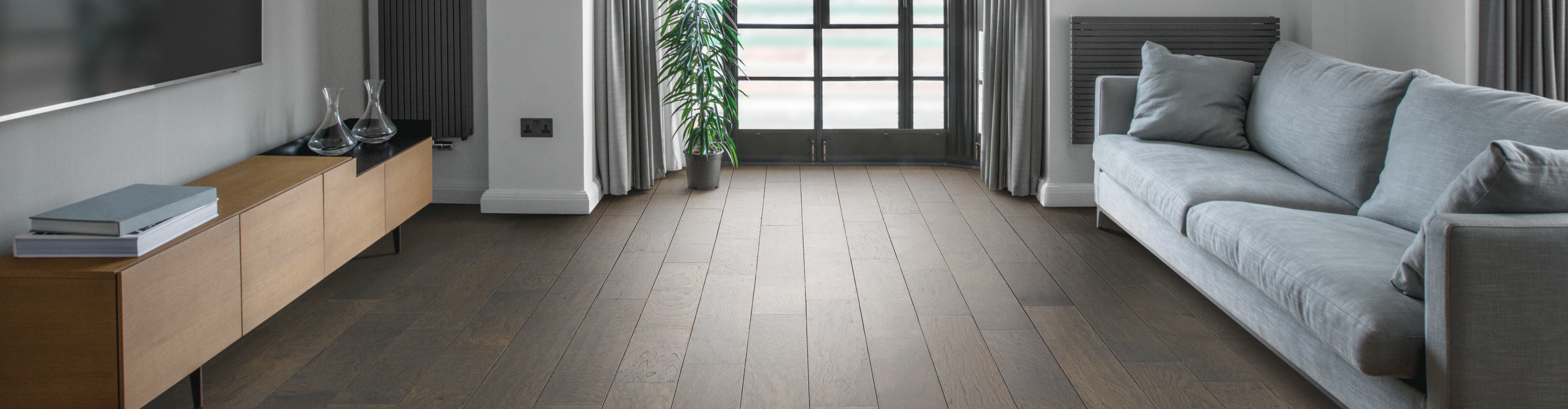 Dark hardwood floor with grey sofa.